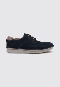 Zapatos de gamuza azul marino con cordones, de textura suave, con acentos beige en contraste y costuras blancas a lo largo de la suela. Diseño de punta redondeada.