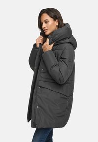 Dark gray puffer coat with a high collar and hood, featuring a zipper and snap closure, quilted texture, and side pockets.