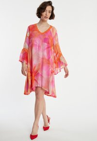 Leichtes Kleid mit Blumenmuster, V-Ausschnitt, Rüschensäumen und asymmetrischem Saum, in Schattierungen von Pink und Orange.
