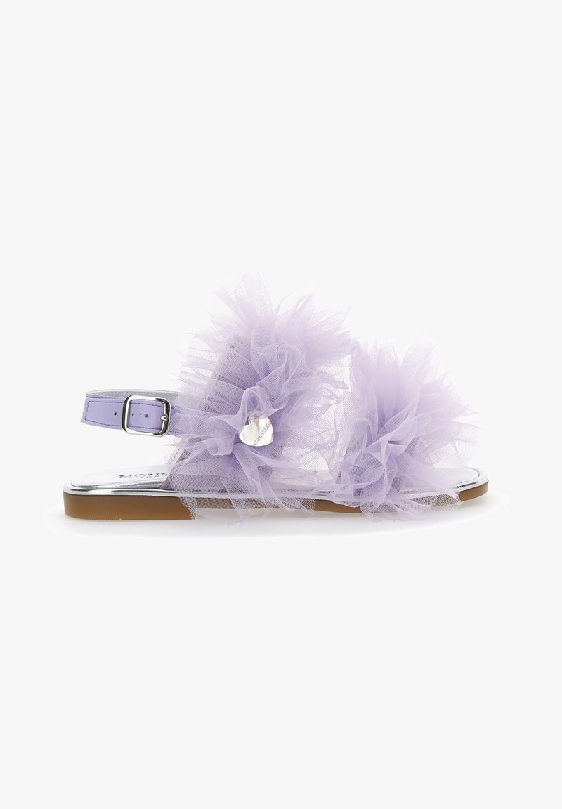 Sandale lilas avec bride à la cheville, semelle plate et grandes décorations florales en tulle recouvrant le dessus et l'avant, ornée d'un petit pendentif en cœur argenté.