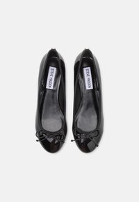 Black patent leather ballet flats featuring a round toe, bow accent on the front, and cushioned interior. The brand label is visible inside.