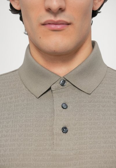 Svetlohnedé polokošeľa s textúrovaným vzorom, na ktorom je slovo "EMPORIO", a s golierom. Má dva tmavé gombíky na krku.
