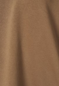 Tessuto marrone con una texture liscia, che mostra un aspetto uniforme e morbido. Nessun motivo o hardware visibile presente.