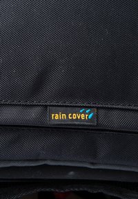 Housse de pluie noire en tissu texturé. Comprend une étiquette de logo visible avec le texte "rain cover" en jaune et des accents bleus.