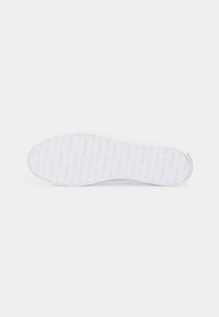 Biała podeszwa do sneakersów z wytłoczonym wzorem nazwy marki, zaokrąglonym kształtem, wykonaną z gumy i minimalistycznym designem.