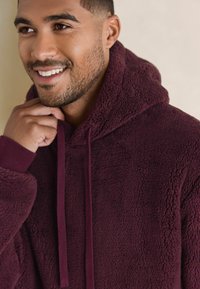 Bordeaux hoodie gemaakt van zacht fleece-materiaal, met trekkoorden en ribgebreide manchetten met een gestructureerde uitstraling.