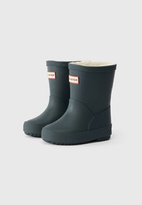Botas de chuva de borracha verde-escuro com um forro macio e branco, apresentando uma ponta redonda, sola texturizada e o logótipo HUNTER vermelho na frente.