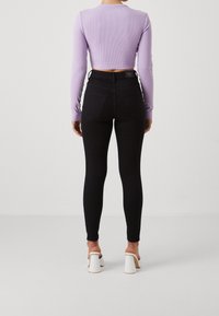 Svarta högmidjade skinny jeans kombinerat med en ljuslila ribbad långärmad crop top, med en figursydd form och skräddarsydda detaljer.