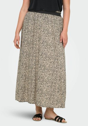 Maxi sukňa v béžovej farbe s čiernymi škvrnami; elastický pás; ľahký materiál; dĺžka po členky; nosená s čiernymi plochými sandálami.