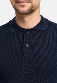 Marineblaue Polohemd aus strukturiertem, geripptem Stoff. Verfügt über einen klassischen Kragen und eine zwei-geteilte Knopfleiste. Weiches, atmungsaktives Material.