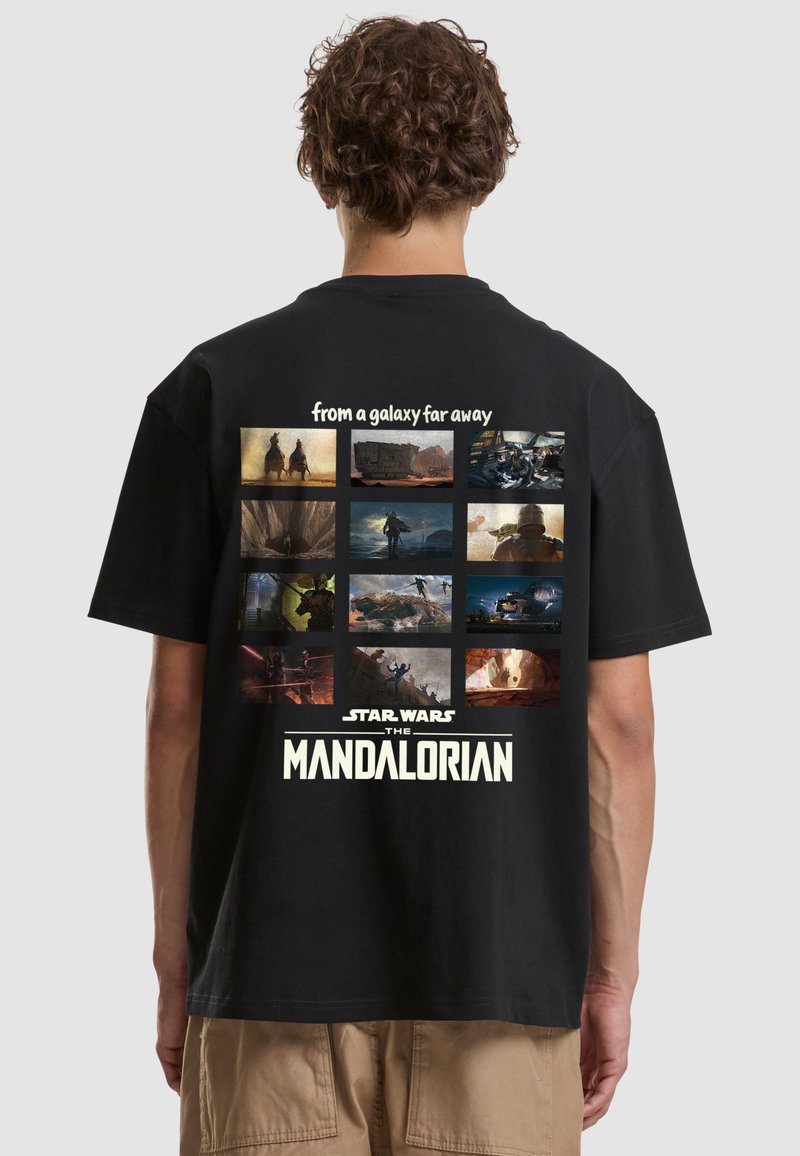 Personne portant un t-shirt noir avec une grille de scènes de The Mandalorian et le texte "d'une galaxie très lointaine" et "Star Wars The Mandalorian."