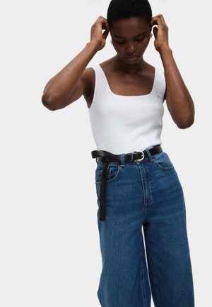 Top en jersey blanc ajusté avec un décolleté carré, associé à un jean large en denim bleu taille haute. Ceinture noire avec une boucle en métal en accent.