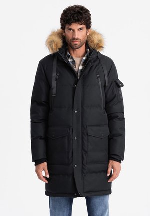 Schwarze gepolsterte Parkajacke mit einer mit Fell gefütterten Kapuze, ausgestattet mit vorderen Knopf-Taschen, Schulterriemen und einem Reißverschluss. Strukturiertes Material.