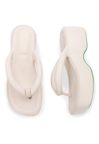Des tongs blanches au design épuré, avec un matériau lisse et une semelle légèrement surélevée avec une accentuation verte le long du bord.