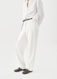 Λευκό παντελόνι καμωμένο κατά παραγγελία με ίσια γραμμή, λεία υφή και πλαϊνές τσέπες, σε συνδυασμό με σκούρα καφέ μοκασίνια και μαύρη ζώνη.