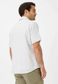 Camicia a maniche corte a righe in grigio chiaro e bianco, con colletto classico e vestibilità rilassata. Il tessuto appare testurizzato e traspirante.