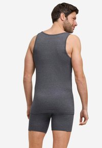 Canottiera grigia e pantaloni corti abbinati realizzati in morbido tessuto elasticizzato. Il design presenta un collo rotondo e una silhouette aderente, con cuciture minime.