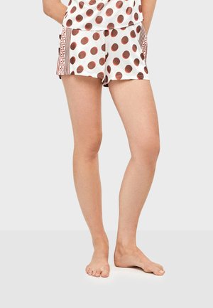 Pantalones cortos blancos con grandes lunares marrones, con bolsillos laterales y detalles de rayas verticales. Tela ligera; ajuste casual y suelto.