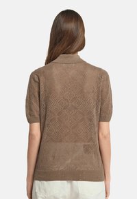 Brunstickad kortärmad tröja med diamantmönster, ribbad krage och nederkant. Strukturerad finish med subtila öppningar överallt.