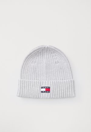 Gray knitted beanie featuring a ribbed texture and a folded cuff. Includes a rectangular logo patch with red, white, and blue accents.