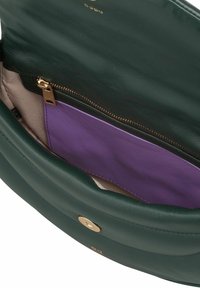 Borsa a tracolla in pelle verde scuro con chiusura dorata, che mostra un compartimento aperto contenente una tasca con zip con dettagli in pelle viola all'interno.