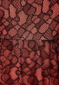 CZARNY koronkowy materiał z fakturowanym wzorem nieregularnych kształtów na tle koralowym, z lekko zgromadzonym brzegiem u dołu.