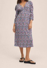 Robe midi à fleurs avec un décolleté en V, des manches trois-quarts, et des couleurs variées, notamment rose, bleu et violet sur un fond sombre.