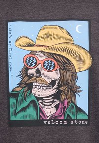 Grafisk T-shirt med et skelet iført en gul cowboyhat og lyserøde solbriller, illustreret mod en blå baggrund med tekst.