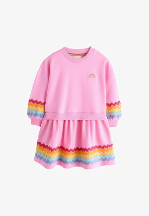 Vaaleanpunainen puuvillamekko, jossa on pyöreä pääntie, pitkät puffihihat ja röyhelöinen hame, jonka helman väliin on kudottu värikkäitä sahalaitakuviota. Rengasmaalaus rinnassa.