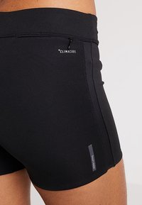 Pantalones cortos deportivos negros con una tela suave y elástica. Cuenta con un bolsillo con cremallera y el logo "CLIMACOOL" cerca de la cintura.