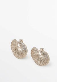 Boucles d'oreilles argentées métalliques en forme de coquillage spiralé, avec des détails texturés et un fermoir à clou.