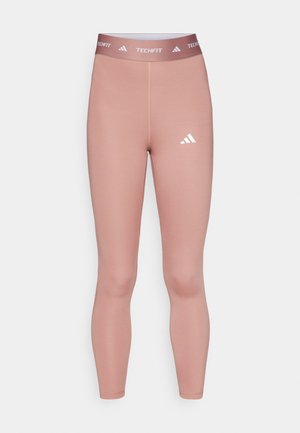 Techfit legingi maigas rozā krāsā, izgatavoti no elastīga materiāla, ar piegulošu dizainu un baltu logotipu apakšējā kājā un josta.