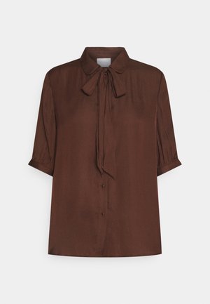 Brun bluse med krave og en bindedetalje ved halsen. Korte pufærmer og knaplukning foran, lavet af et glat stof.