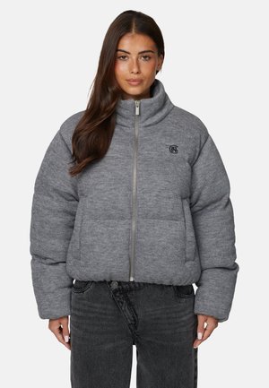 Wygodna szara kurtka z wysokim kołnierzem, zamkiem błyskawicznym z przodu i logo. Posiada szerokie, pikowane sekcje oraz długie rękawy. Noszona z ciemnymi dżinsami.