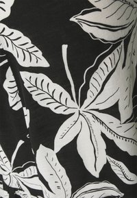 Bomuldsstof med en sort baggrund prydet med store hvide botaniske blade, omkranset af sort med fine detaljer og varierende teksturer.