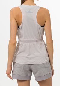 Lichtgrijze sporttanktop met een racerbackontwerp, gemaakt van een gestructureerde stof en met een aansluitende taille, gecombineerd met losse grijze shorts.