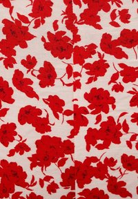 Bílá látka s hustým červeným květinovým vzorem, který obsahuje květy a listy různých velikostí, uspořádané náhodně po celé ploše.