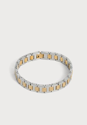 Bracelet à maillons argent et or avec des sections carrées en or comportant de petits cristaux incrustés, présenté fermé sur un fond clair uni.