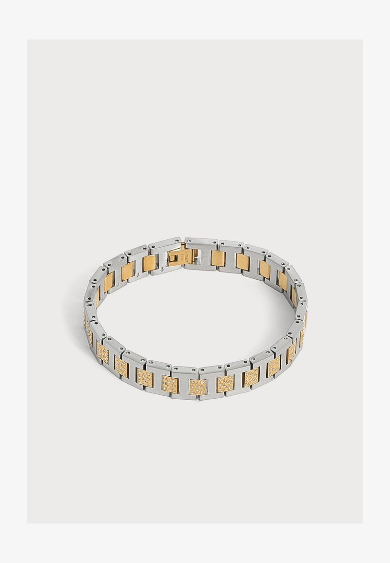 Bracelet à maillons argent et or avec des sections carrées en or comportant de petits cristaux incrustés, présenté fermé sur un fond clair uni.