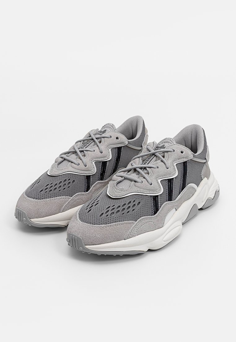 Szare sportowe sneakersy z mieszanką siateczki i zamszu, z masywną podeszwą, wiązanym designem i subtelnymi czarnymi paskami akcentującymi.