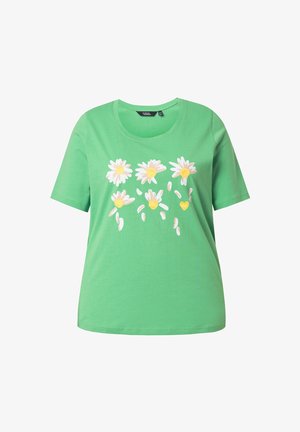 T-shirt en coton vert avec un col rond, présentant un motif floral de marguerites blanches et jaunes, avec des pétales éparpillés en dessous.