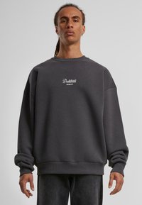 Mørkegrå sweatshirt lavet af blødt stof, med rund hals, dropped skuldre og et lille hvidt logo på brystet.