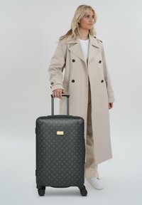 Maleta rígida negra con patrón de diamante, ruedas resistentes y un mango retráctil. Presenta una placa de logo dorada.