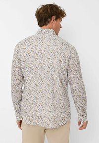 Langärmliges Hemd mit einem hellen Hintergrund, das ein florales Muster in Gelb, Grau und Lila zeigt. Der Stoff wirkt leicht und glatt.