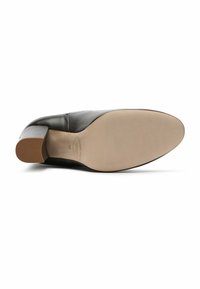 Zapato de cuero negro con un tacón bajo en bloque, punta redonda y una textura suave. La suela es beige con un sutil estampado de la marca.