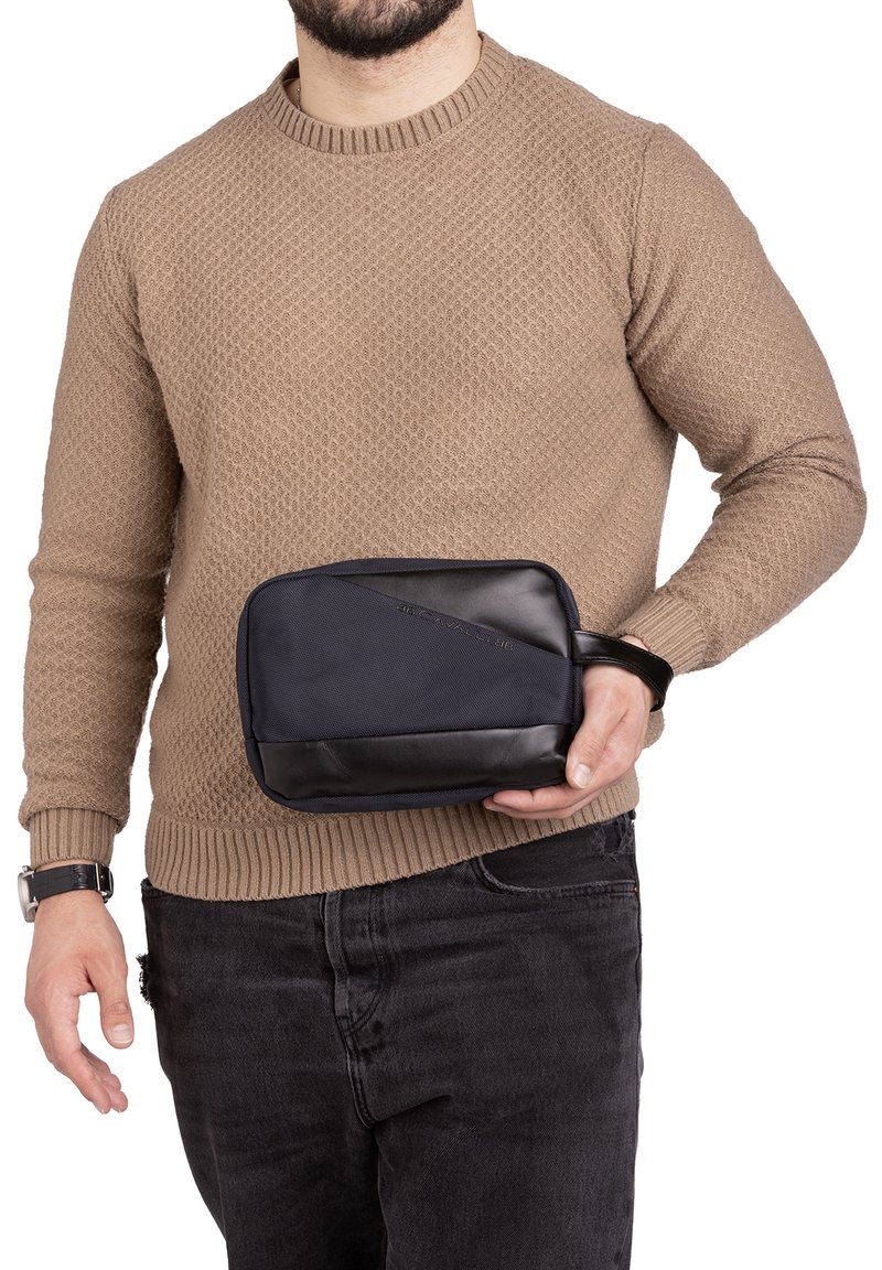 Pochette da viaggio compatta in tessuto blu navy con un elegante dettaglio in pelle nera. Forma rettangolare con chiusura a zip; dotata di una maniglia corta.
