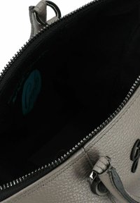 Grijze leren handtas met een gestructureerd oppervlak, ritsluiting en een zwarte binnenkant met een blauw logo label zichtbaar.