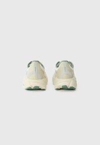 Hellebeige Sportschuhe mit einem Obermaterial aus Mesh, grünen Akzenten und einer klobigen weißen Sohle. Verfügt über einen gepolsterten Kragen und eine strukturierte Außensohle.