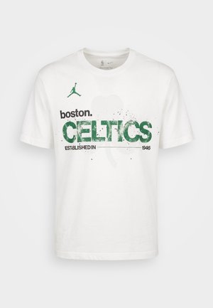 Camiseta blanca de Nike con texto verde "boston. CELTICS Established in 1946" y un gráfico tenue de trébol en el fondo.