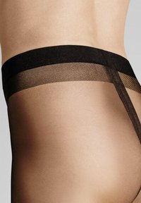 Durchsichtige schwarze Strumpfhosen mit einem breiten, weichen schwarzen Bund im Fischgrätmuster. Glatte Oberfläche mit einem leicht gebräunten Erscheinungsbild.